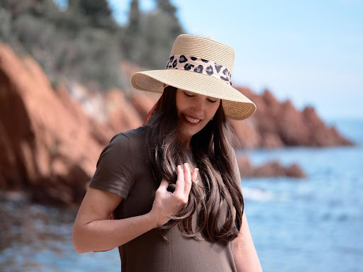 Photo d'une femme avec un chapeau, debout sur une plage.