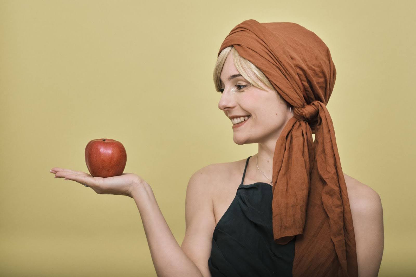 Photo d'une femme qui tient et regarde une pomme dans sa main. 