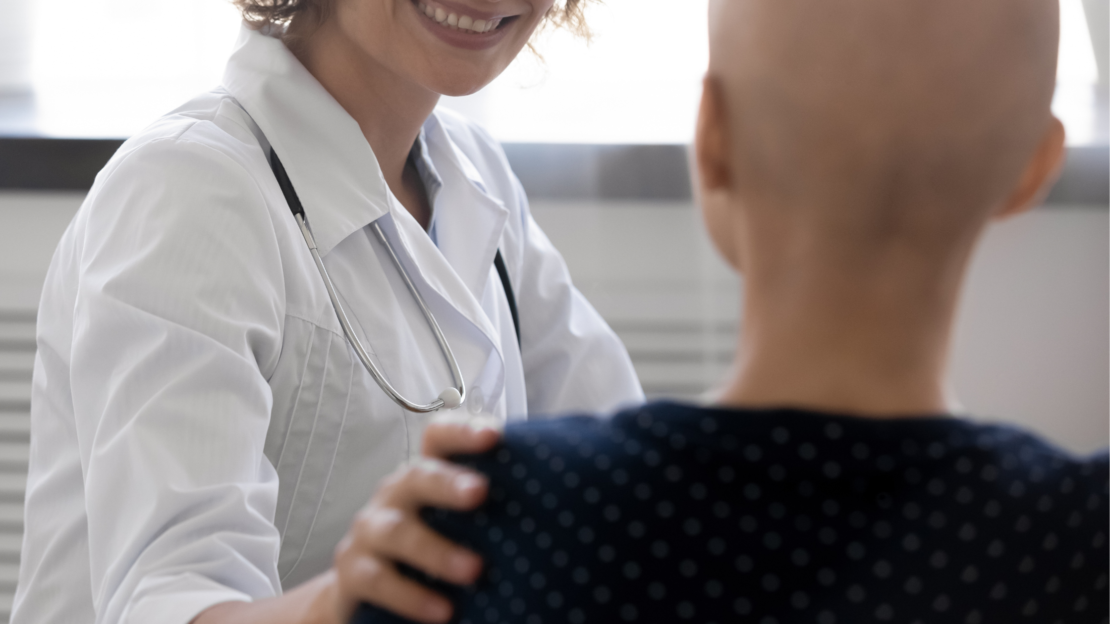 Photo d'un médecin qui pose la main sur l'épaule d'une patiente en lui souriant. 