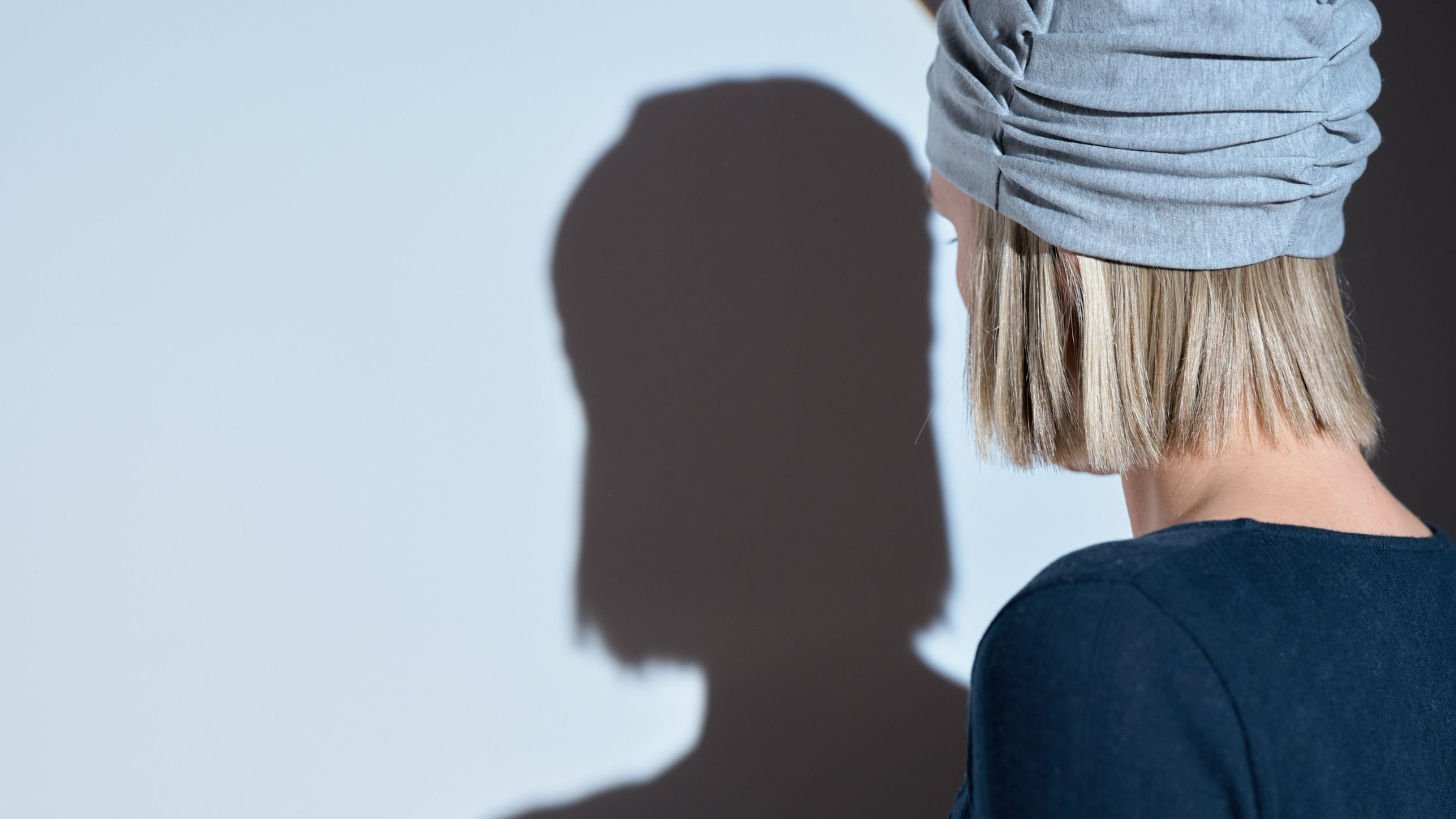 Photo d'une femme de fos, qui regarde son ombre sur un mur. 