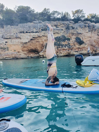 Photo de Julie qui fait une posture inversée de Yoga sur une planche de paddle. 