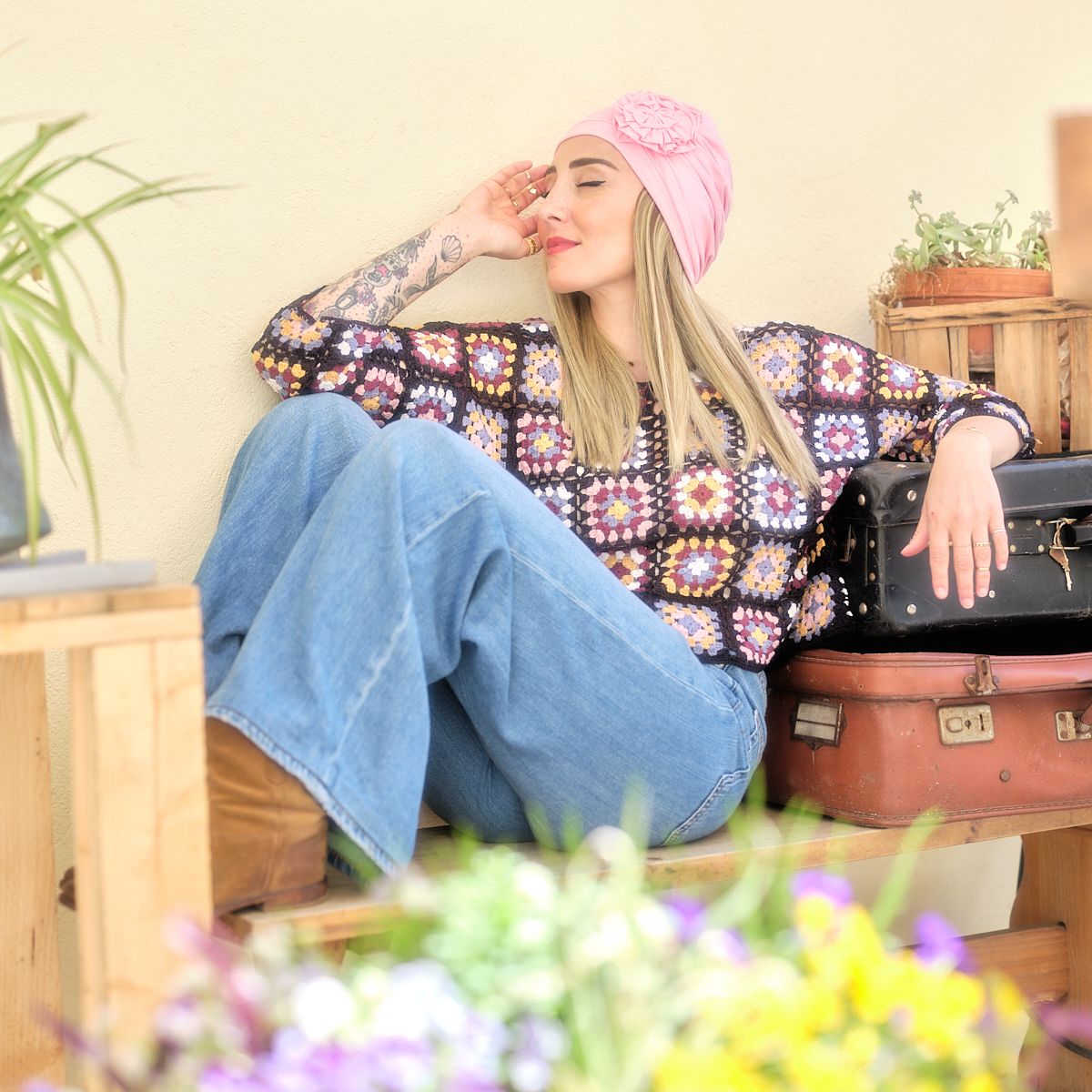 Photo de Julie assise qui porte un jean, un pull et un bonnet rose. 