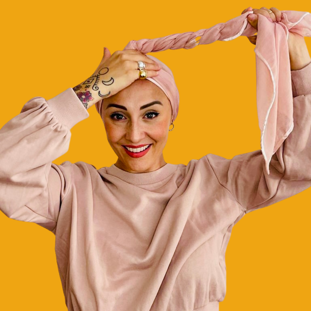 Femme qui noue un turban rose autour de sa tête